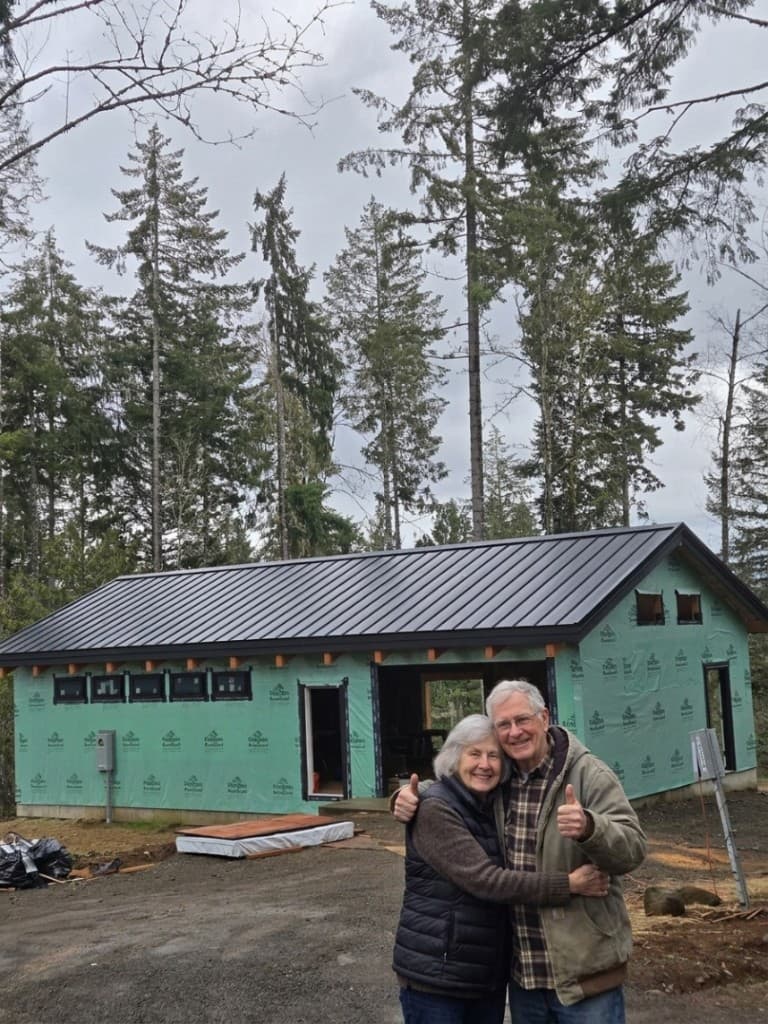 Happy customers giving thumbs-up in front of their home with a new black metal roof